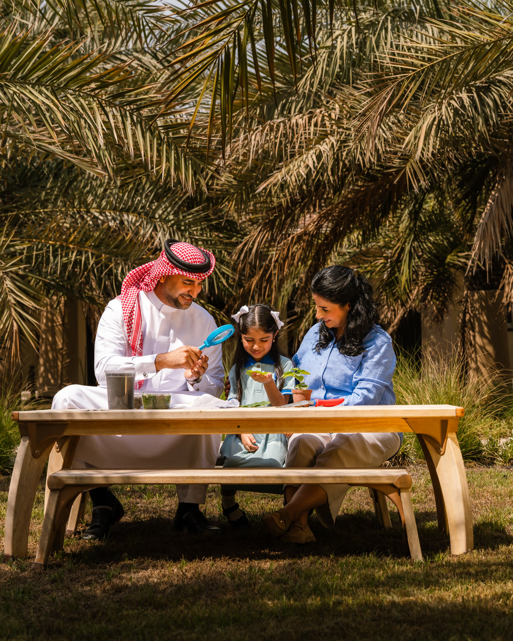 A family examines a plant together in the school garden.