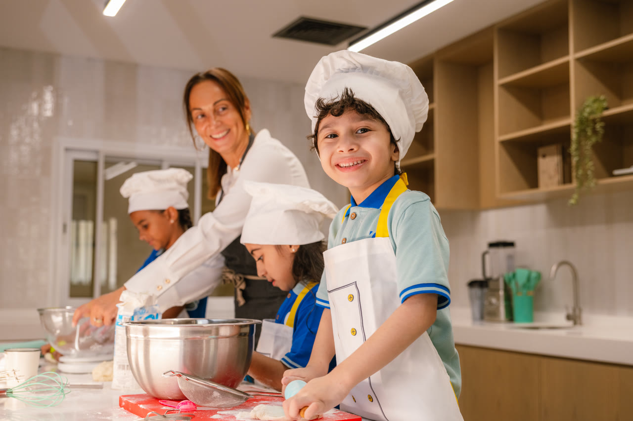 A learner smiles while preparing food in the kitchen lab.