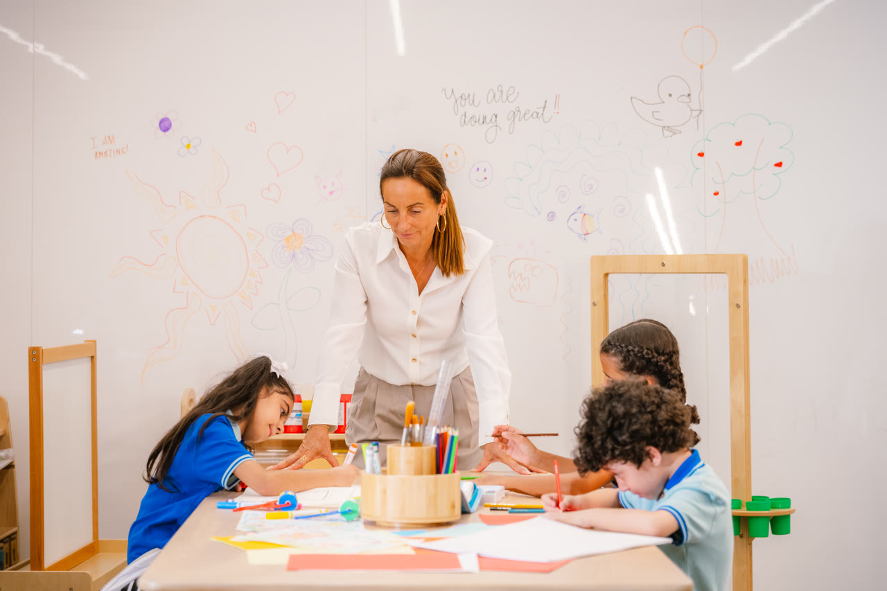 An adult supports learners creating artwork together.
