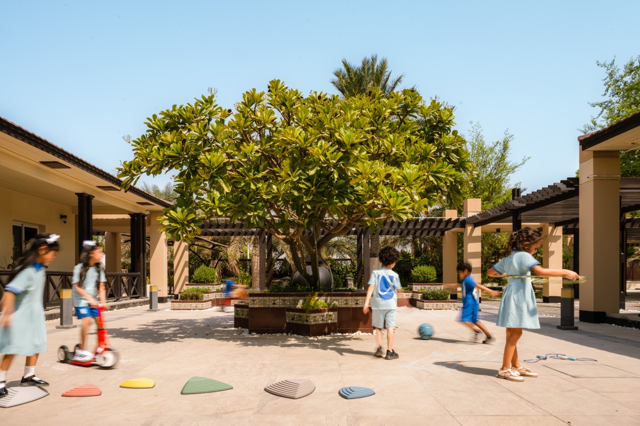 Children play with scooters and stepping stones in Alphera’s courtyard.